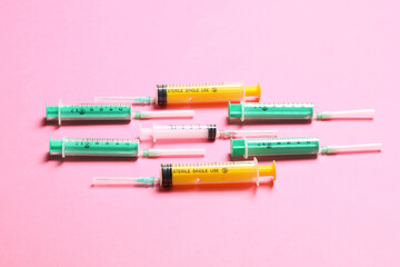 Top view of medical syringes with needles at pink background with copy space. Injection treatment concept