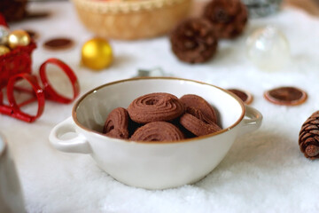 Cup of tea or coffee, glass of wine or juice, bowl of cookies, organic pomegranate, fluffy blanket, pine cones, various Christmas decorations and lit candles on the table. Christmas hygge concept.