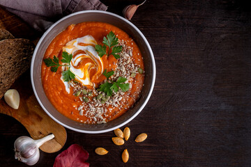Pumpkin cream soup with sesame seeds, sunflower seeds and yogurt on a dark table