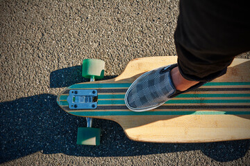 Crop skater standing on longboard with striped pattern