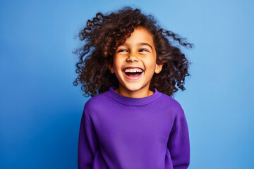Portrait d'un enfant afro américain portant un pull violet sur fond bleu