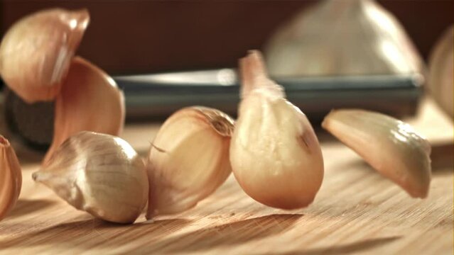 Fresh garlic falls on a cutting board. Filmed on a high-speed camera at 1000 fps. High quality FullHD footage