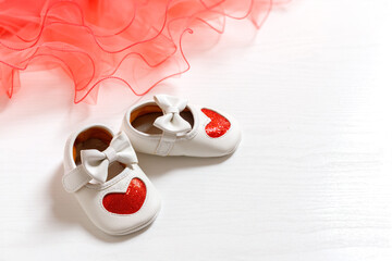 Children's white shoes with a heart design and a pink fabric. Greeting card. Top View