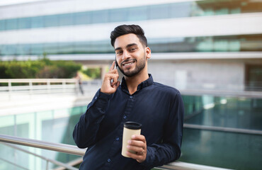 Middle Eastern business man talking on cellphone near office center