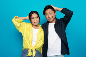 Pensive confused korean millennial couple in casual scratching heads with hands, think