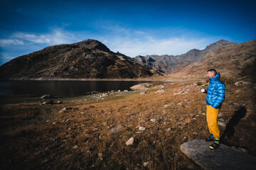 Bergsteiger mit blauer Jacke und Kaffee schaut in die aufgehende Sonne