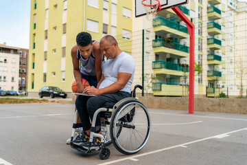 The coach in the wheelchair shows the young black man the statistics from the previous game before they start training