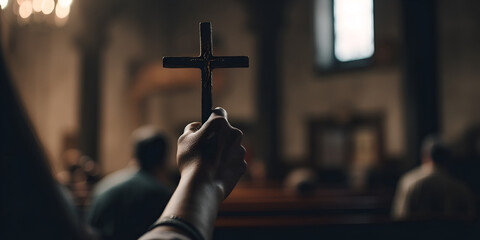 Hand holding a cross in church during prayers, Mass in the Catholic Church,  - obrazy, fototapety, plakaty