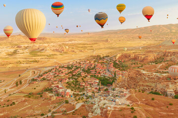 Balloons into Cappadocia's vast skyline. The brilliant hues of balloons capture dwindling daylight, casting a mesmerizing illumination on the surreal peaks below them in Goreme, Cappadocia in Turkey.