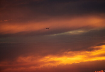 鮮やかな夕焼けの空と飛行中の旅客機の風景