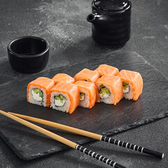  Fresh Salmon Sushi Rolls on Dark Slate with Soy Sauce and Chopsticks