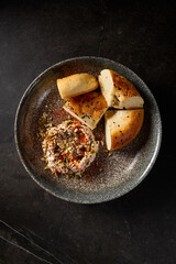 A vertical top view of hummus accompanied by Uzbek tandoor bread, beautifully presented on a dark ceramic plate