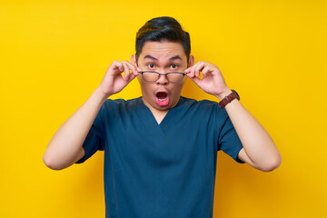 Surprised young Asian man doctor or nurse wearing a blue uniform take off his glasses and opens his...