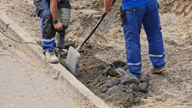 Roadworks Construction Site Conctractor Replacing Concrete Curb Brick using Shovel and Pneumatic Hammer