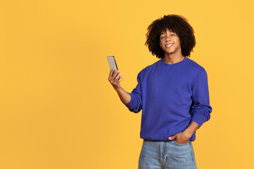 Happy Young Black Guy Using Mobile Phone And Smiling At Camera