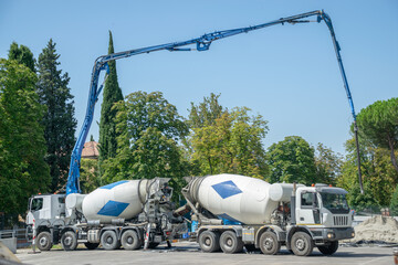 Pair of Cement trucks with extended hydraulic systems pouring cement