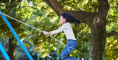 秋の公園でブランコを遊んでいる小学生の女の子の様子