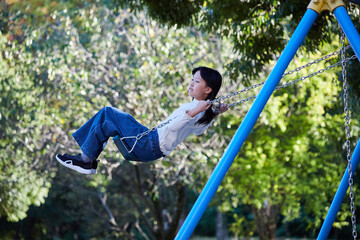 秋の公園でブランコを遊んでいる小学生の女の子の様子