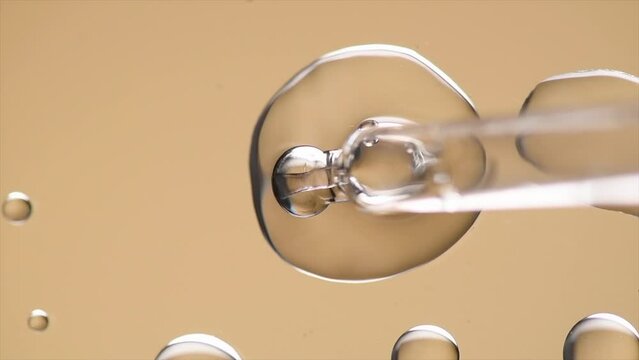 Cosmetic dropper with serum, beauty cosmetics dripping, on beige background. Macro shot. Serum, peptides, beauty and health care products. Glass pipette with liquid ,close up. Top view. Skin care 