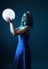 Close up portrait of beautiful female model with blue hair wearing glamorous  fantasy ball gown,...