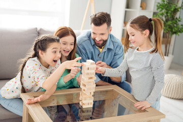 Portrait of lovely funny careful cheerful family building pile stack pyramid support generation...