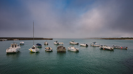 Fototapeta premium A small harbour on the west coast of France with ships at anchor on a foggy day.