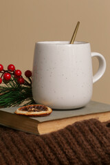 Cozy winter lifestyle concept. Cup of hot drink with vintage book and warm knitted clothes.