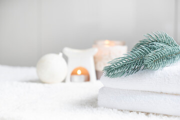 Fresh white towels with fir branch, candles and Christmas decorations. Wellness and wellbeing. SPA massage or beauty salon, relaxation and self care in Christmas or New Year variant. Copy space.
