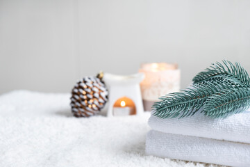 Obraz na płótnie Canvas Fresh white towels with fir branch, candles and Christmas decorations. Wellness and wellbeing. SPA massage or beauty salon, relaxation and self care in Christmas or New Year variant. Copy space.