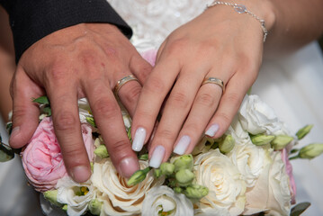 Obraz na płótnie Canvas the bride and groom show their wedding rings on the bride's bouquet