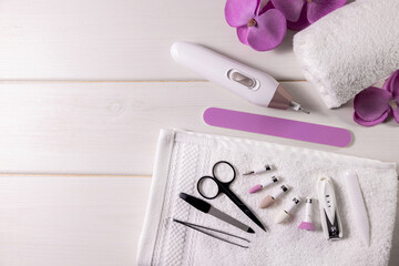 Obraz na płótnie Canvas manicure pedicure tools kit. cordless nail drill machine with accessories on white table with copy space. nail care