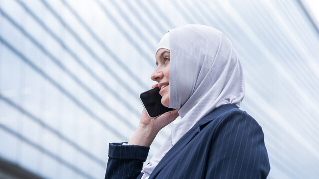 Business woman in hijab and suit talking on smartphone. 