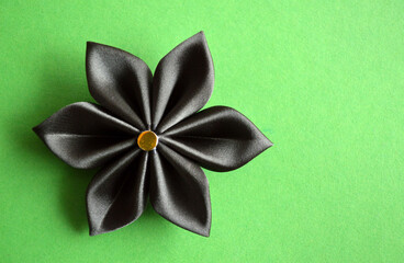 Black fabric flower isolated on green background with copy space