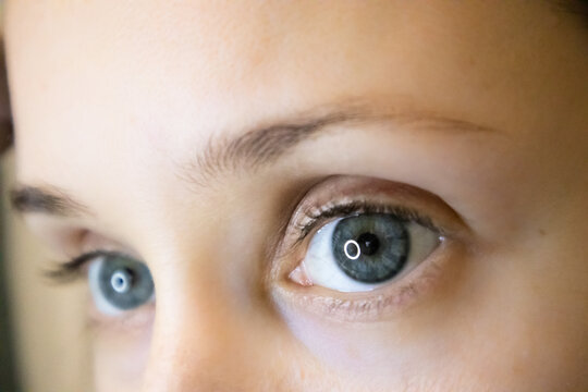 Female eyes up close. Blue-eyed white European girl wearing colored contact lenses looking to the right. Beautiful woman's eyes. Healthy eyes, good clear vision. Eyeball, eyebrows, eyelid, eyelashes.