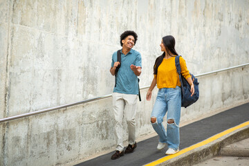 Full body smiling young couple with bags walking on street © mimagephotos