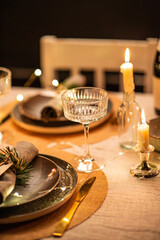 winter holidays, dinner party and celebration concept - close up of champagne saucer glass and scandinavian christmas table serving with burning candles at home at night - obrazy, fototapety, plakaty
