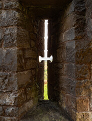 A cross-shaped arrowslit, a narrow opening through which archers, crossbowmen or musketeers fired weapons, at Carreg Cennen Castle in Carmarthenshire, South Wales.