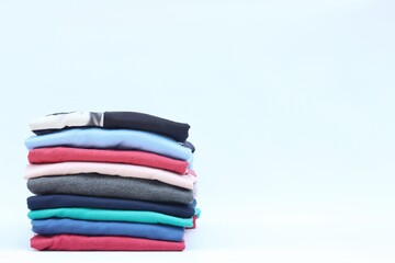 Collection of colorful plain t-shirts is stacked on the table. isolated on white background