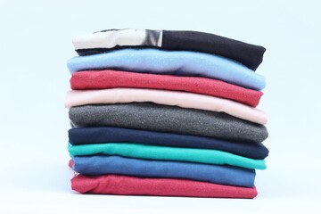 Collection of colorful plain t-shirts is stacked on the table. isolated on white background