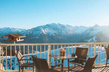 Balcony with table and chairs overlooking the snow-capped mountains of the Zell am See ski resort in Austria. Sunny winter day, vacation in the Alps. Relaxing photo without people