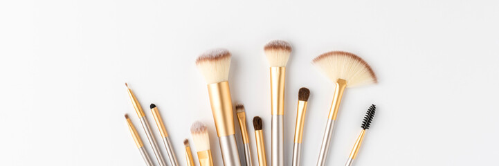 Collection of beautiful makeup brushes on white background with copyspace. Top view