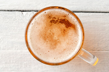 Overhead shot of cold beer glass on white wooden background with copyspace