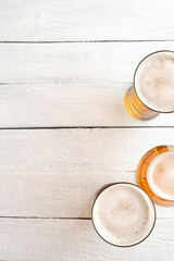 Overhead shot of beer mugs on white wooden background with copyspace. Close up