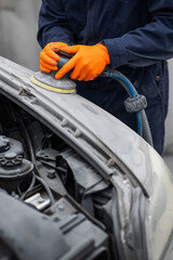 A mechanic sands the putty on a car body with a machine. Repair after an accident. 