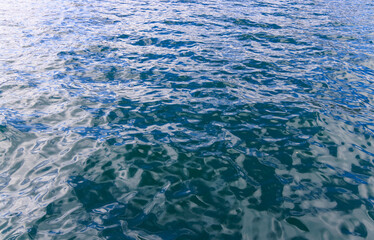 Obraz premium Small ripples reflect morning sun on calm ocean water