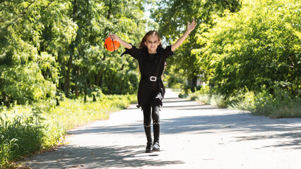 Fototapeta premium Happy Halloween. Cute little witch with a pumpkin in the hands.