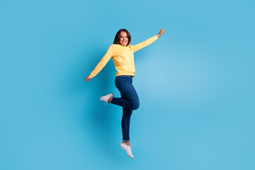 Fototapeta premium Carefree woman jumping against blue background