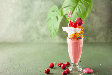 Homemade monster milkshake. Freak shake. Cerry extreme shake with sweets on green background. ...