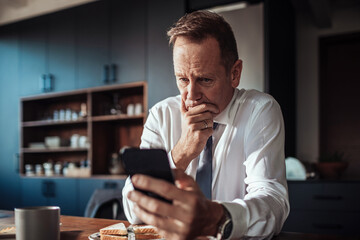 Focused businessman reading a message on his phone at home