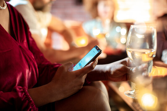 Woman in a red dress browsing her smartphone during a gathering
